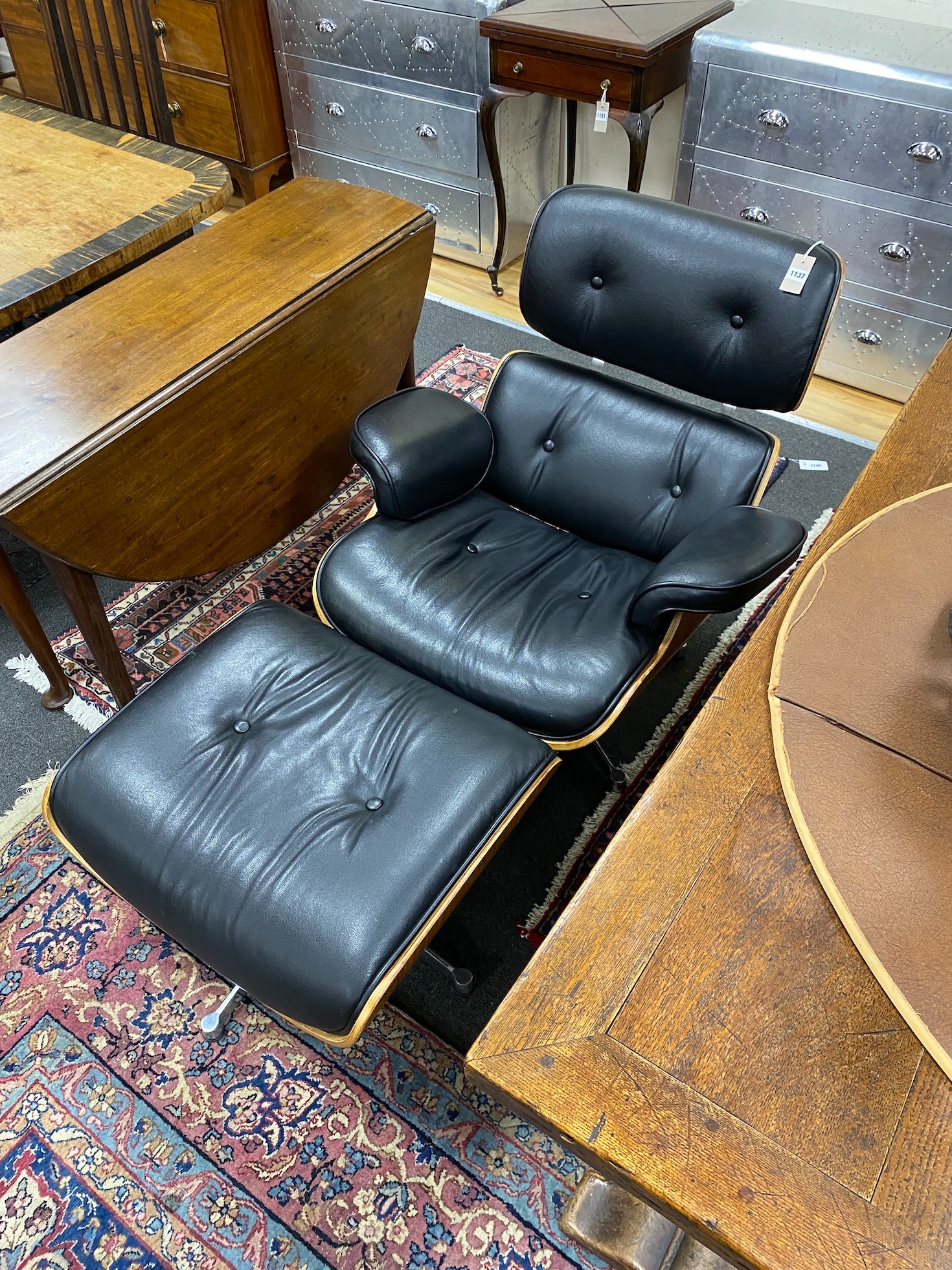 An Eames-style black leather armchair and footstool